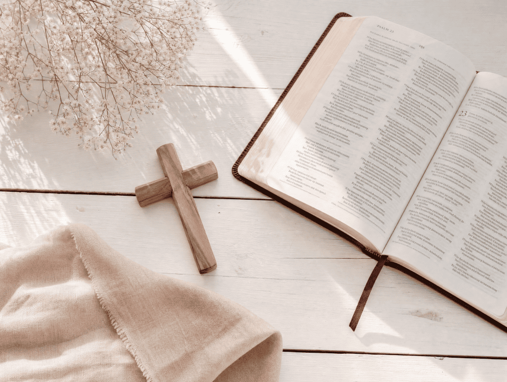 Open Bible with highlighted scripture passage and wooden cross bathed in soft natural light