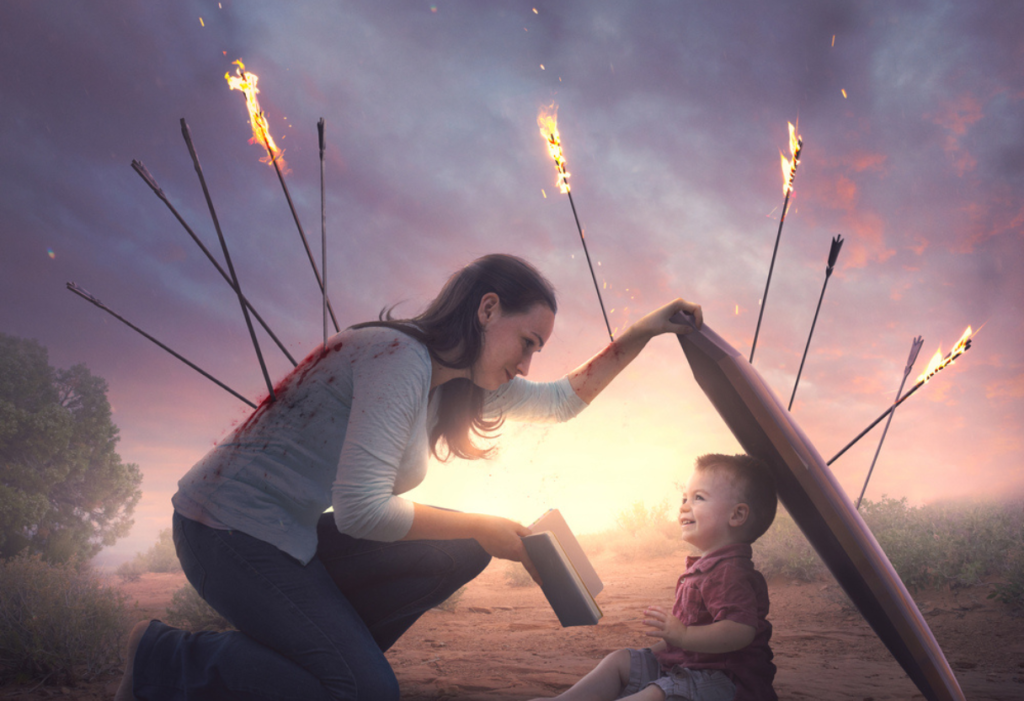 mom holding open bible in front of small child while holding a shield over child to block arrows with fire