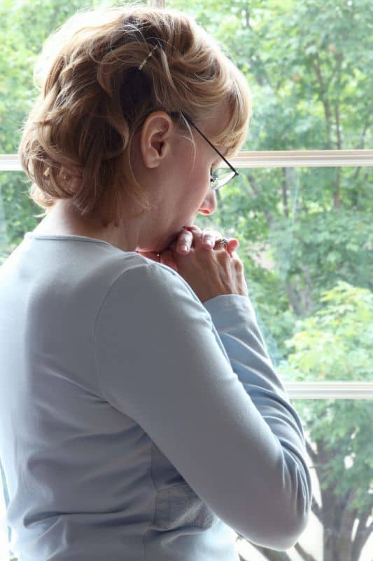 woman standing at window praying for 10 effective prayers to change your life