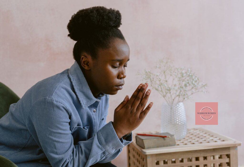 woman sitting on a chair with hands folded praying
