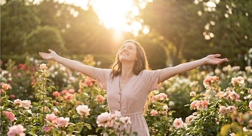 A joyful Christian woman standing in a sunlit rose garden with her arms wide open, learning how to fight spiritual warfare and stand firm in faith.